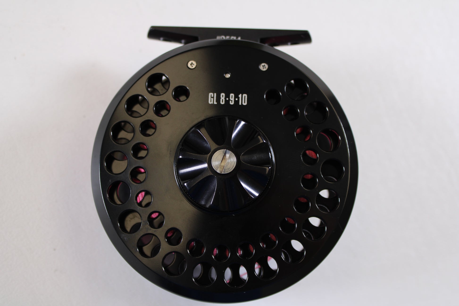 A close-up of a G. Loomis GL 8-9-10 with Spare Spool—Used Fly Reel in excellent condition, featuring multiple circular cutouts, photographed on a white background—ideal for our Rod and Reel Trade-In Program.