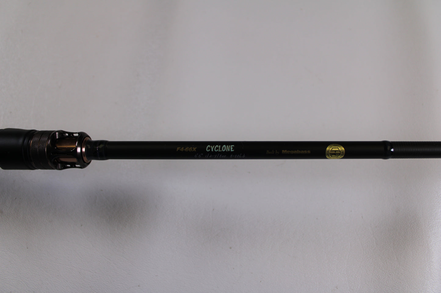 A close-up of the Megabass Destroyer P5 F4-66X Used Casting Rod in excellent condition, featuring a gold logo and text, is displayed as part of our Rod and Reel Trade-In Program against a plain white background.