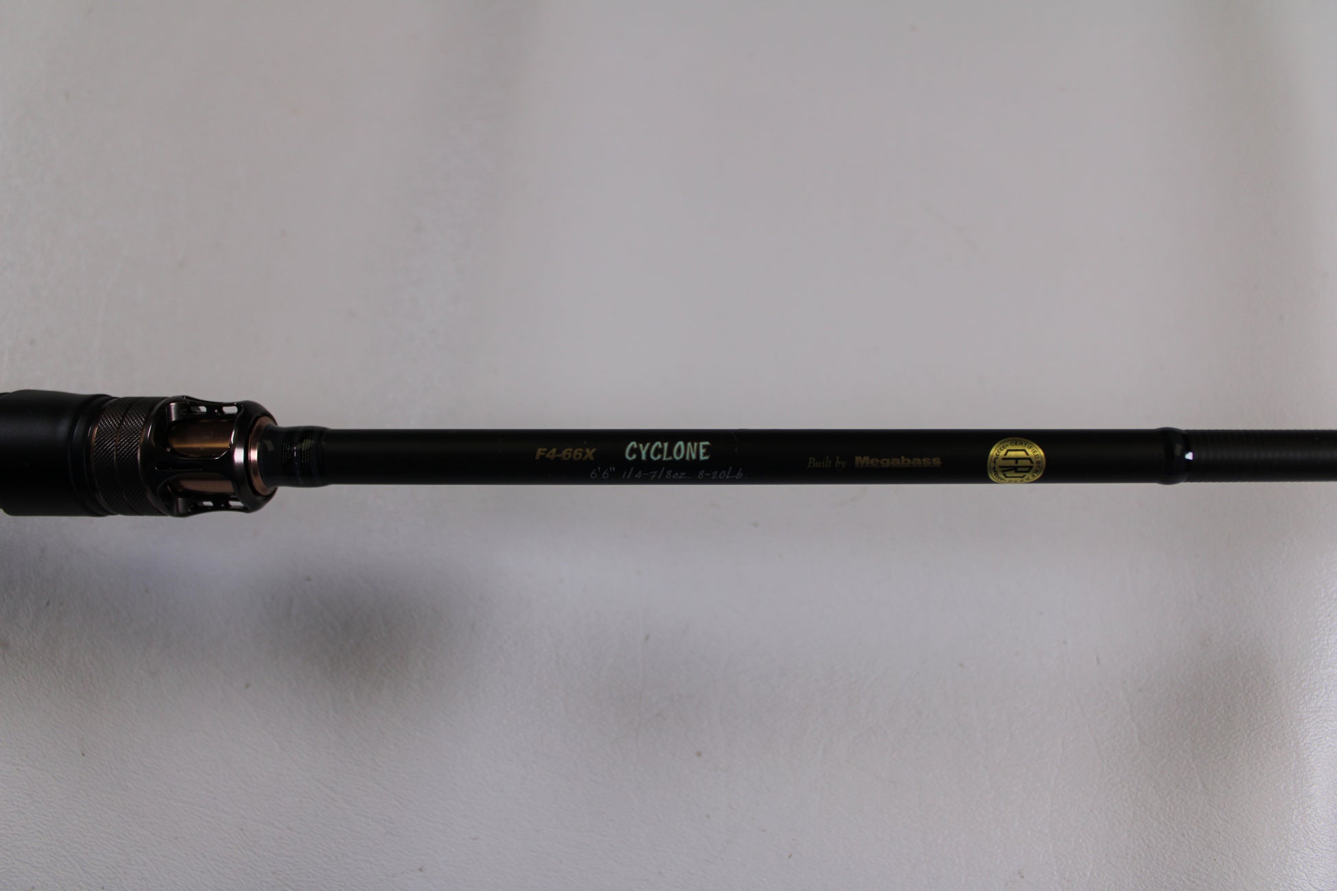 A close-up of the Megabass Destroyer P5 F4-66X Used Casting Rod in excellent condition, featuring a gold logo and text, is displayed as part of our Rod and Reel Trade-In Program against a plain white background.