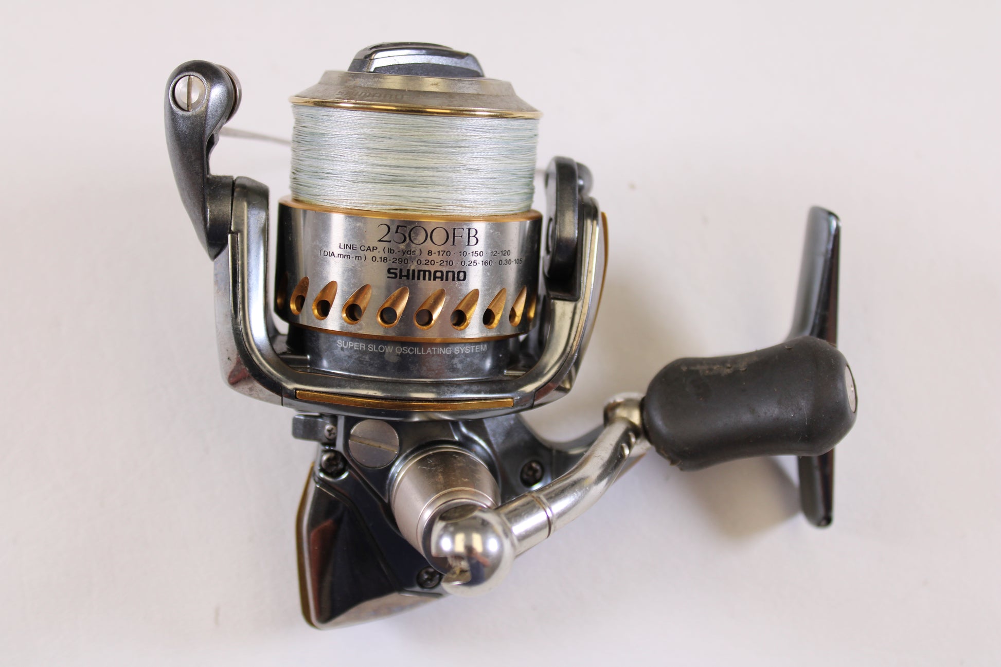 A close-up of a Shimano Stella FB 2500FB used spinning reel in very good condition with fishing line on the spool, set against a white background—ideal for those seeking quality pre-owned Shimano gear.