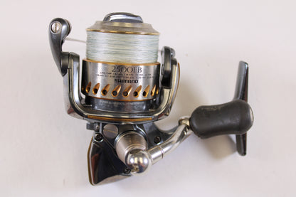 A close-up of a Shimano Stella FB 2500FB used spinning reel in very good condition with fishing line on the spool, set against a white background—ideal for those seeking quality pre-owned Shimano gear.