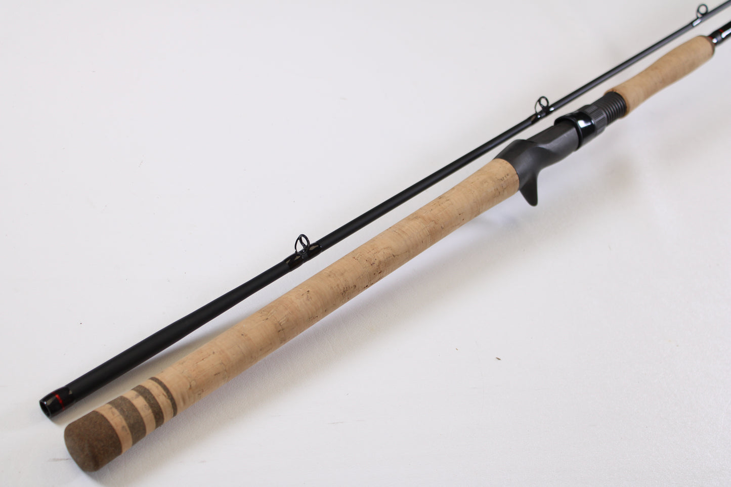 The G. Loomis Salmon & Steelhead IMX 1084-2C SATR 9'0" Used Casting Rod in excellent condition lies diagonally on a white surface—ideal for those seeking quality used gear or trading in rods and reels for store credit.