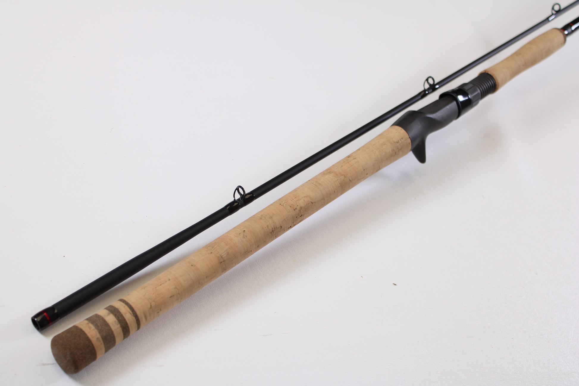 The G. Loomis Salmon & Steelhead IMX 1084-2C SATR 9'0" Used Casting Rod in excellent condition lies diagonally on a white surface—ideal for those seeking quality used gear or trading in rods and reels for store credit.