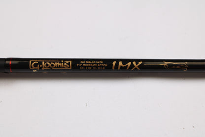 A close-up of a black G. Loomis Salmon & Steelhead IMX 1084-2C SATR 9'0" used casting rod in excellent condition, ideal for gear enthusiasts or trade-ins. The label displays the gold specs and fish outline graphic.