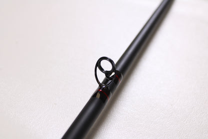 A close-up of the G. Loomis Salmon & Steelhead IMX 1084-2C SATR 9'0" Used Casting Rod in excellent condition, featuring a metal guide ring, is shown against a plain white background.