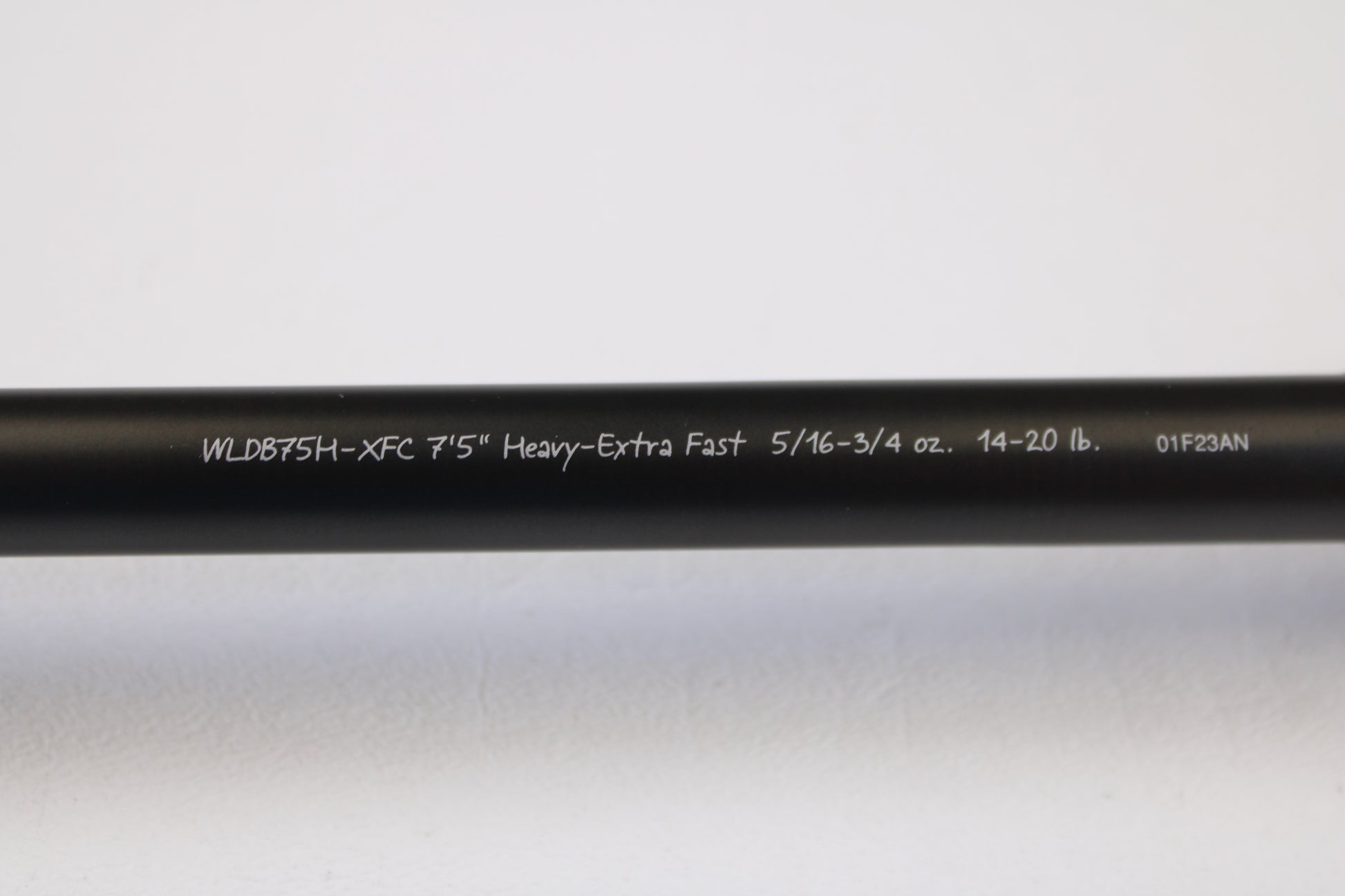 A close-up of the Fenwick World Class Bass WLDB75H-XFC 7'5" Heavy used casting rod in excellent condition, featuring white specs on a black blank, photographed against a white background and eligible for our rod and reel trade-in program.