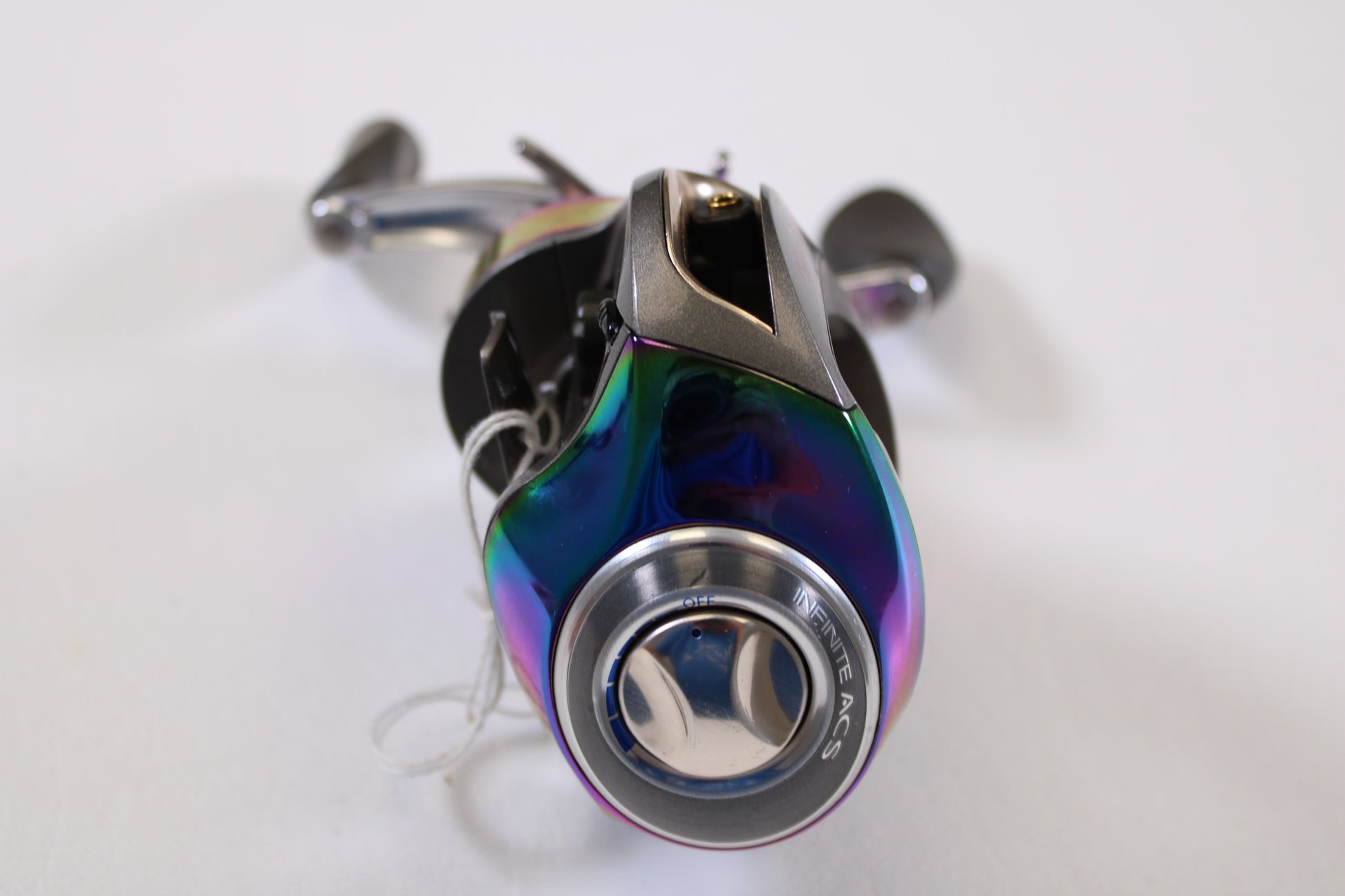 A close-up of a shiny Quantum Energy PT E770PT 7.0:1 RH casting reel in very good condition, featuring a rainbow metallic finish and "HITE ACS" knob—ideal for upgrading with our rod and reel trade-in program.