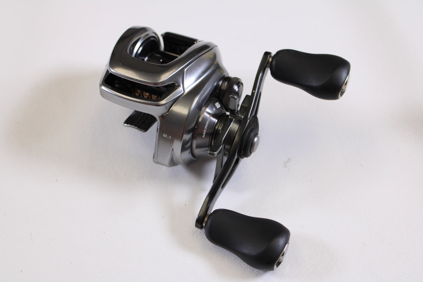 A close-up of the Shimano Bantam MGL BANTAMMGL151XG 8.1:1 LH Used Casting Reel in excellent condition with black handles—ideal for anyone seeking quality used Shimano gear or participating in our Rod and Reel Trade-In Program.