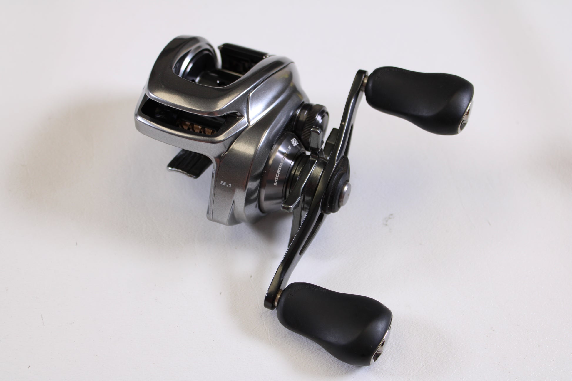 A close-up of the Shimano Bantam MGL BANTAMMGL151XG 8.1:1 LH Used Casting Reel in excellent condition with black handles—ideal for anyone seeking quality used Shimano gear or participating in our Rod and Reel Trade-In Program.