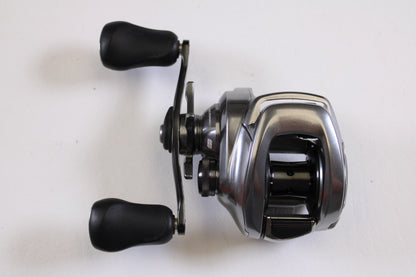 The used Shimano Bantam MGL BANTAMMGL151XG 8.1:1 LH Casting Reel in excellent condition features two black handles and is eligible for our Rod and Reel Trade-In Program—trade it in for store credit and upgrade today!.