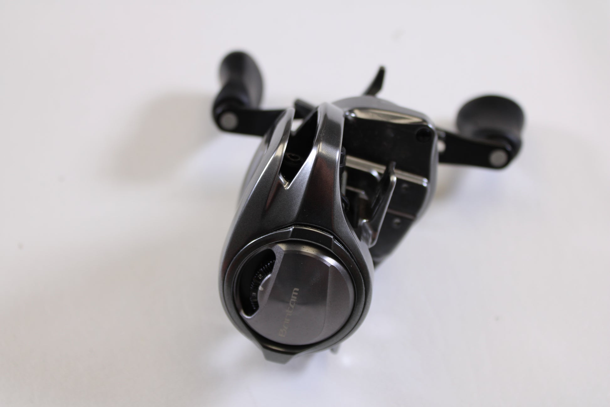 A close-up of a Shimano Bantam MGL BANTAMMGL151XG 8.1:1 LH Casting Reel in excellent used condition, featuring dual handles and adjustment knobs—ideal for your upgrade via our Rod and Reel Trade-In Program.