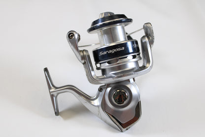 A close-up of a Shimano Saragosa SW A SRG6000SWAHG 5.7:1 spinning reel in silver and black, showing the spool, handle, and bail arm—ideal for those seeking quality used Shimano gear or considering our Rod and Reel Trade-In Program.