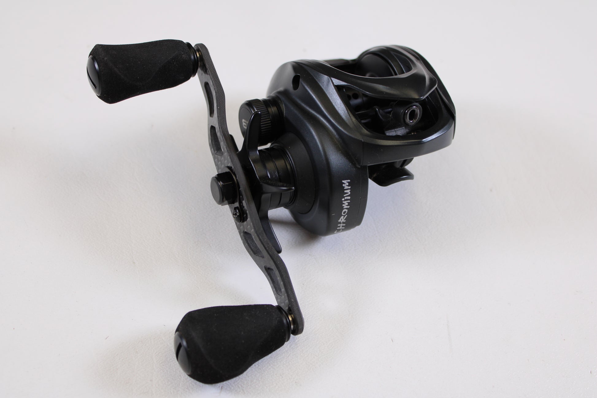 A Kistler Chromium KCR-BK-R173 7.3:1 RH used casting reel in excellent condition, featuring two rubberized handles and stylish metallic and matte black finishes, is shown on a white surface—ideal for savings with our Rod and Reel Trade-In Program.