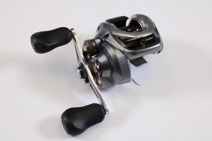 A close-up of a Shimano Curado I CU200I 6.3:1 RH used casting reel in good condition, featuring black handles and shown on a white surface—ideal for anglers seeking reliable, pre-owned Shimano fishing gear.