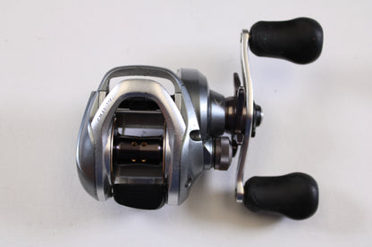 The Shimano Curado I CU200I 6.3:1 RH used casting reel in good condition features a silver and black design with dual black handles—ideal for your fishing gear trade-in or earning store credit.