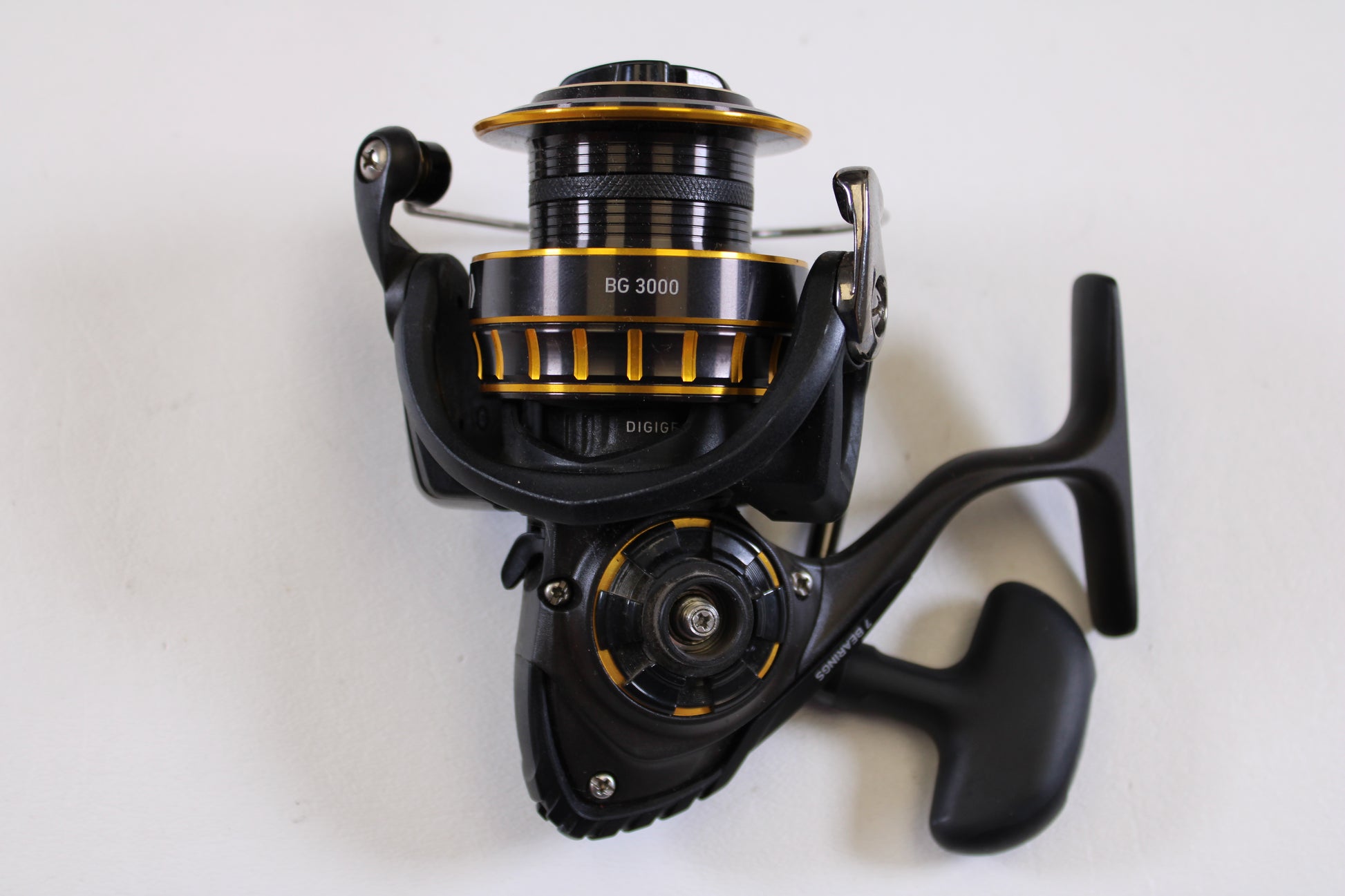 The Daiwa BG BG3000 5.6:1 Used Spinning Reel, in excellent condition, is shown in black and gold against a plain white background. This Daiwa reel features a rotating handle and detailed mechanics—ideal for your next trade-in.