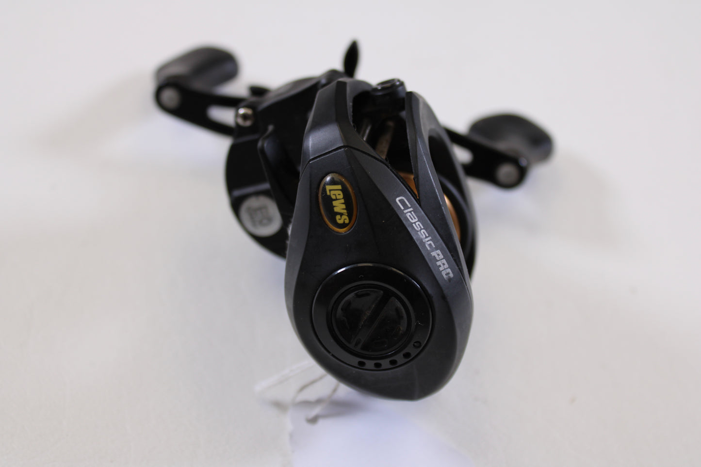 A close-up of a Lew's Speed Spool Classic Pro CP1SH 7.5:1 RH Used Casting Reel in excellent condition on a white surface, highlighting the logo and handle—ideal for our trade-in program or anyone seeking quality used gear.