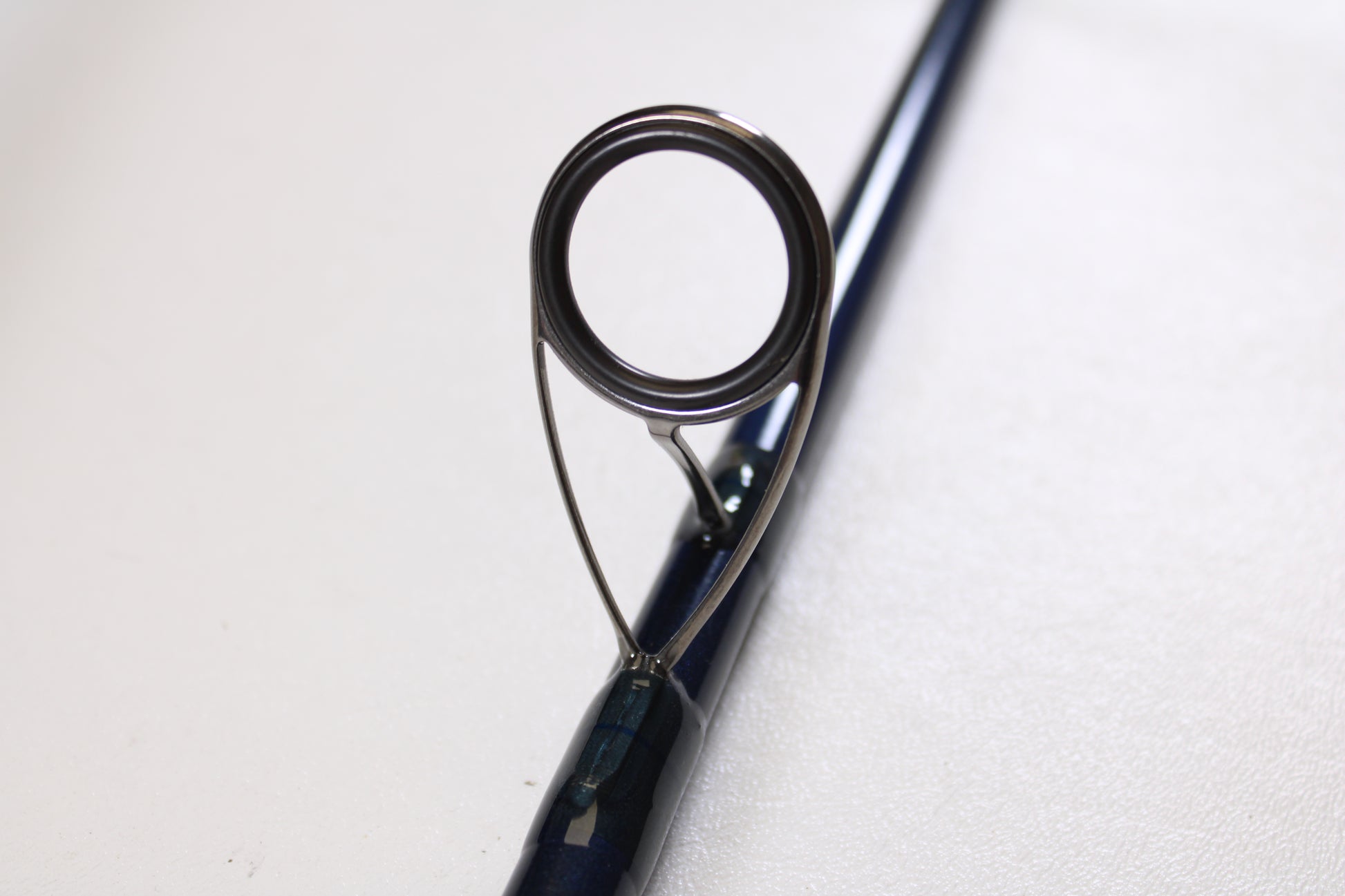 Close-up of a guide ring on a St. Croix Seage SES90MMF2 9'0" Medium 2 Piece Used Spinning Rod (Excellent Condition), available through our Rod and Reel Trade-In Program for store credit. Plain light background.