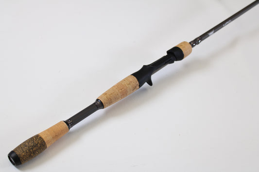The Fenwick HMG Bass HMGB610MH-FC 6'10" Medium Heavy Casting Rod, in excellent used condition, features a cork handle and black reel seat. Great for anglers trading in gear or seeking top value through our rod and reel trade-in program.