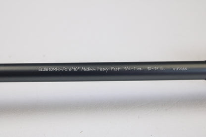 A Fenwick Elite Bass ELB610MH-FC 6'10" Medium Heavy used casting rod in very good condition, featuring white model details on a black finish, ideal for rod and reel trade-ins. Shown on a white surface.