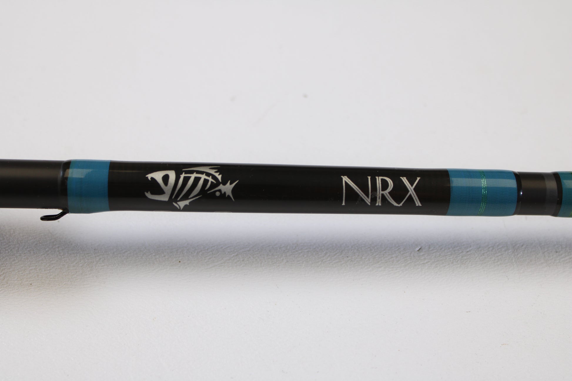A close-up of the G. Loomis NRX 893c JWR 7'5" Medium Heavy Used Casting Rod in very good condition features the NRX logo and fish skeleton graphic—ideal for anglers trading in gear through our Rod and Reel Trade-In Program.