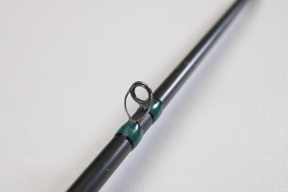 A close-up of a G. Loomis NRX 893c JWR 7'5" Medium Heavy Used Casting Rod in very good condition, highlighting a black line guide with teal thread, on a white background—ideal for our Rod and Reel Trade-In Program.