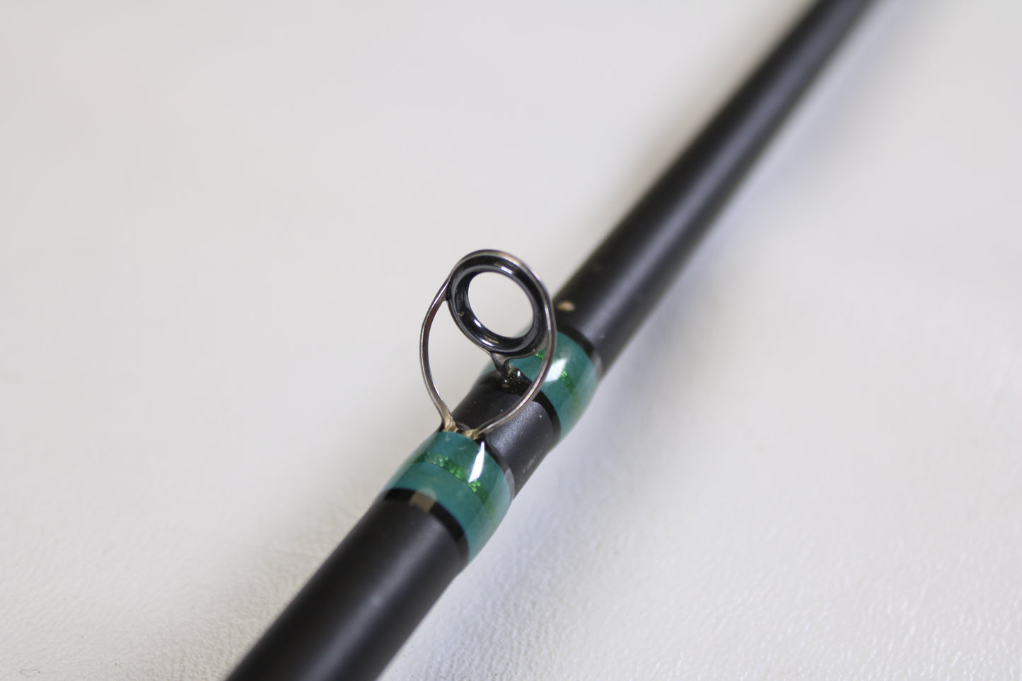Close-up of a G. Loomis NRX 894c JWR 7'5" Heavy Used Casting Rod in excellent condition, featuring a black guide with green thread wraps—perfect for those trading in gear or maximizing store credit.