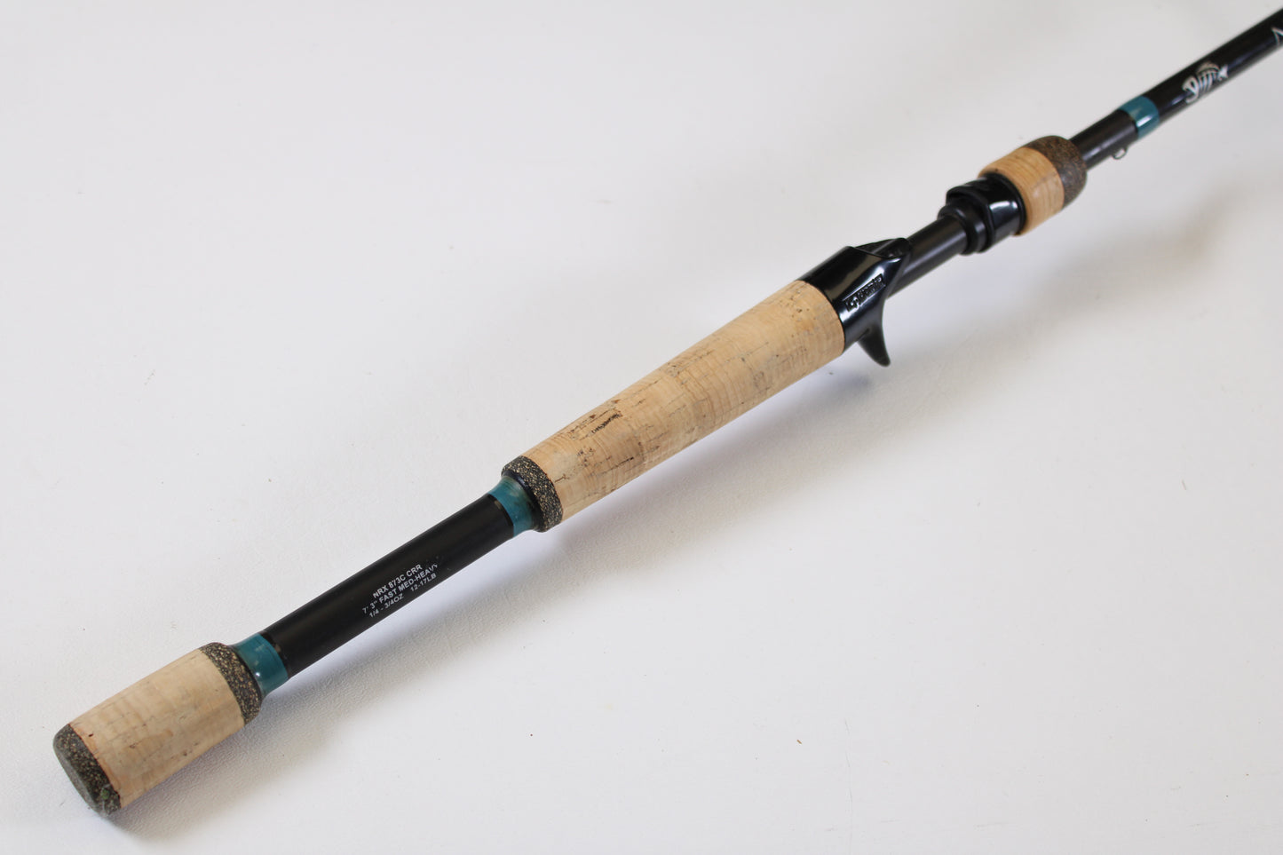A close-up of a G. Loomis NRX 873c CRR 7'3" Medium Heavy Used Casting Rod in excellent condition, featuring a cork handle and black reel seat—ideal for upgrading with our rod and reel trade-in program.
