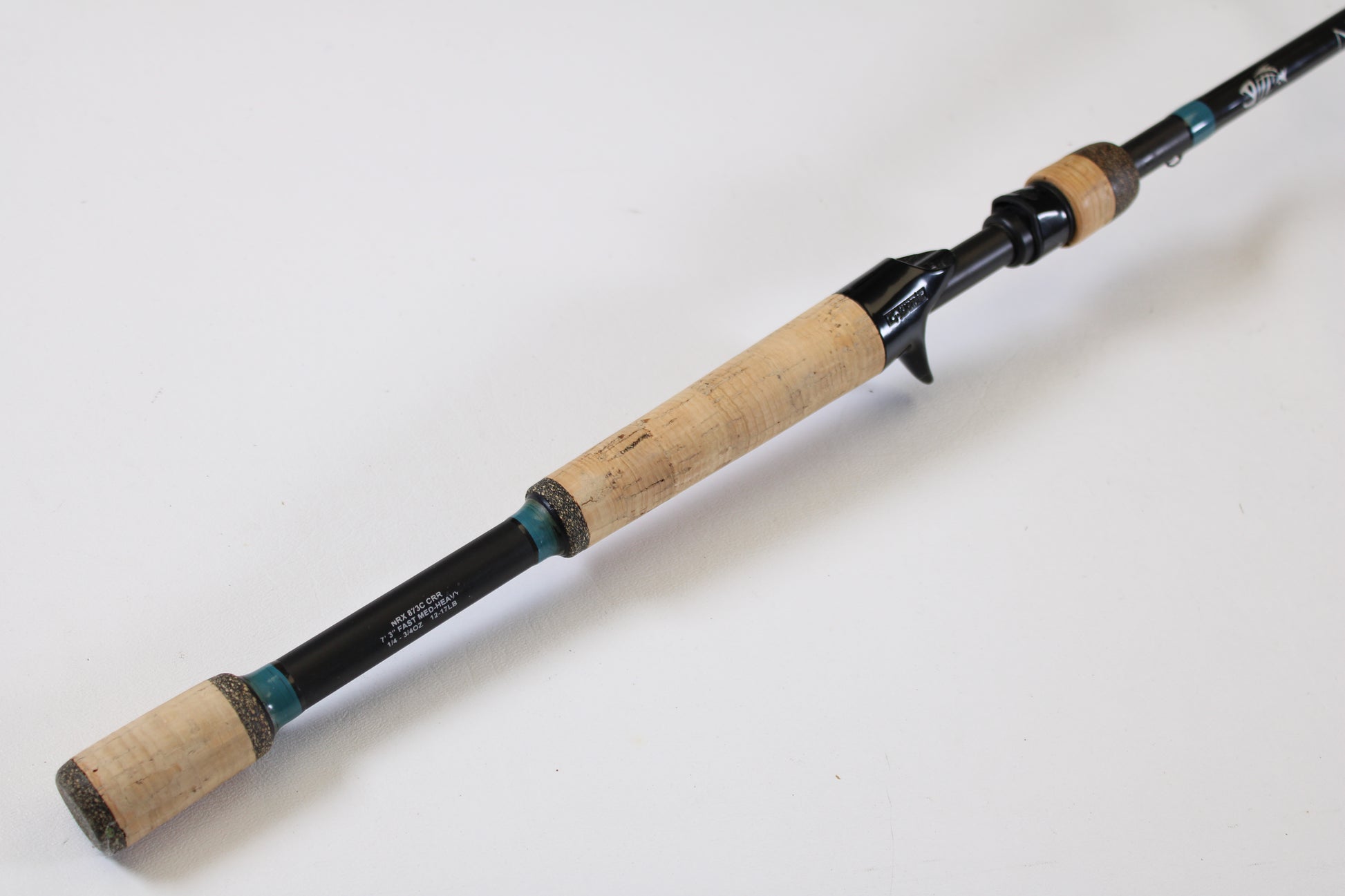 A close-up of a G. Loomis NRX 873c CRR 7'3" Medium Heavy Used Casting Rod in excellent condition, featuring a cork handle and black reel seat—ideal for upgrading with our rod and reel trade-in program.