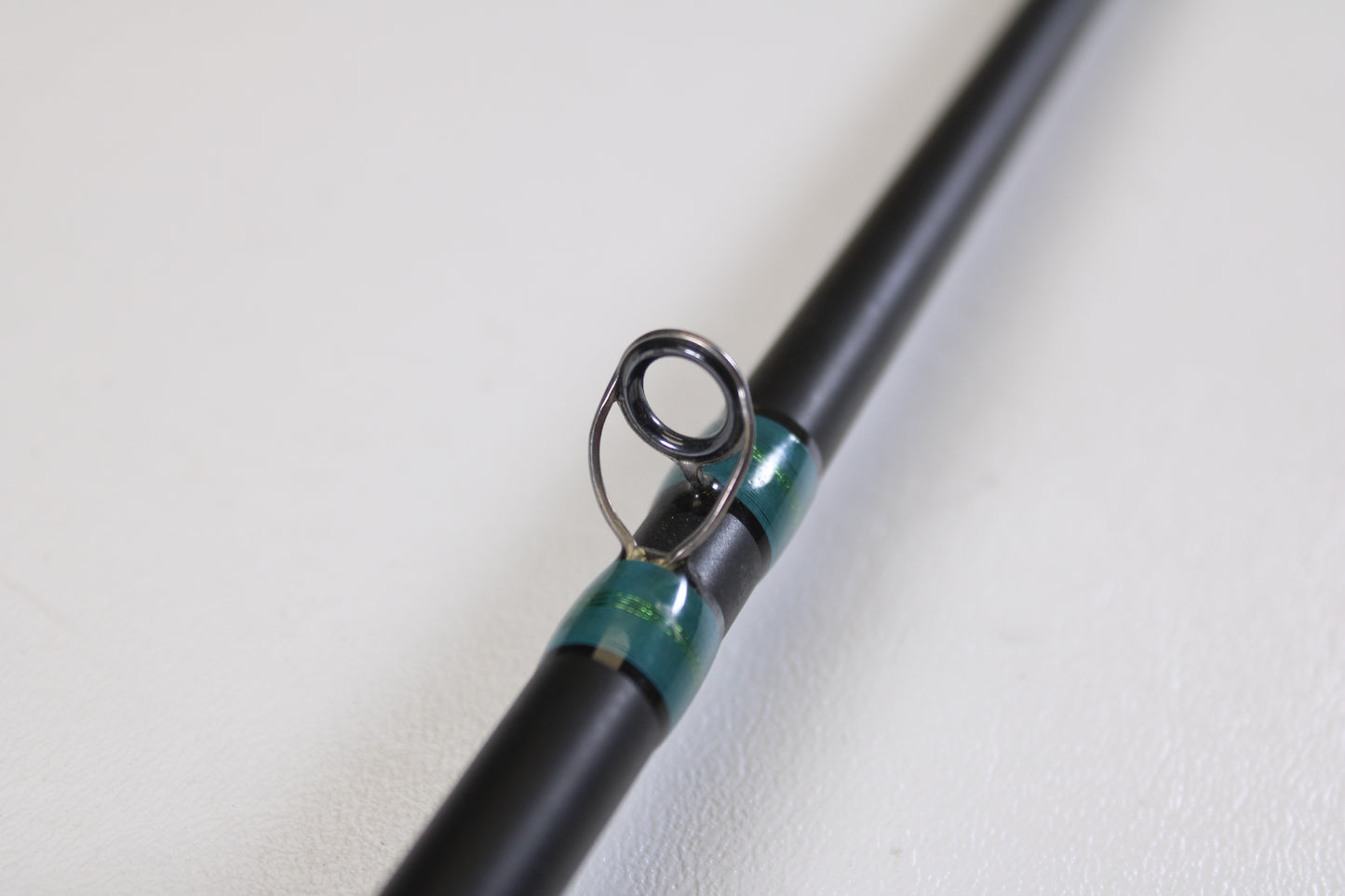 A close-up of the G. Loomis NRX 873c CRR 7'3" Medium Heavy used casting rod in excellent condition, featuring black guides with metallic green thread wraps—ideal for trade-in or earning store credit with G. Loomis gear.