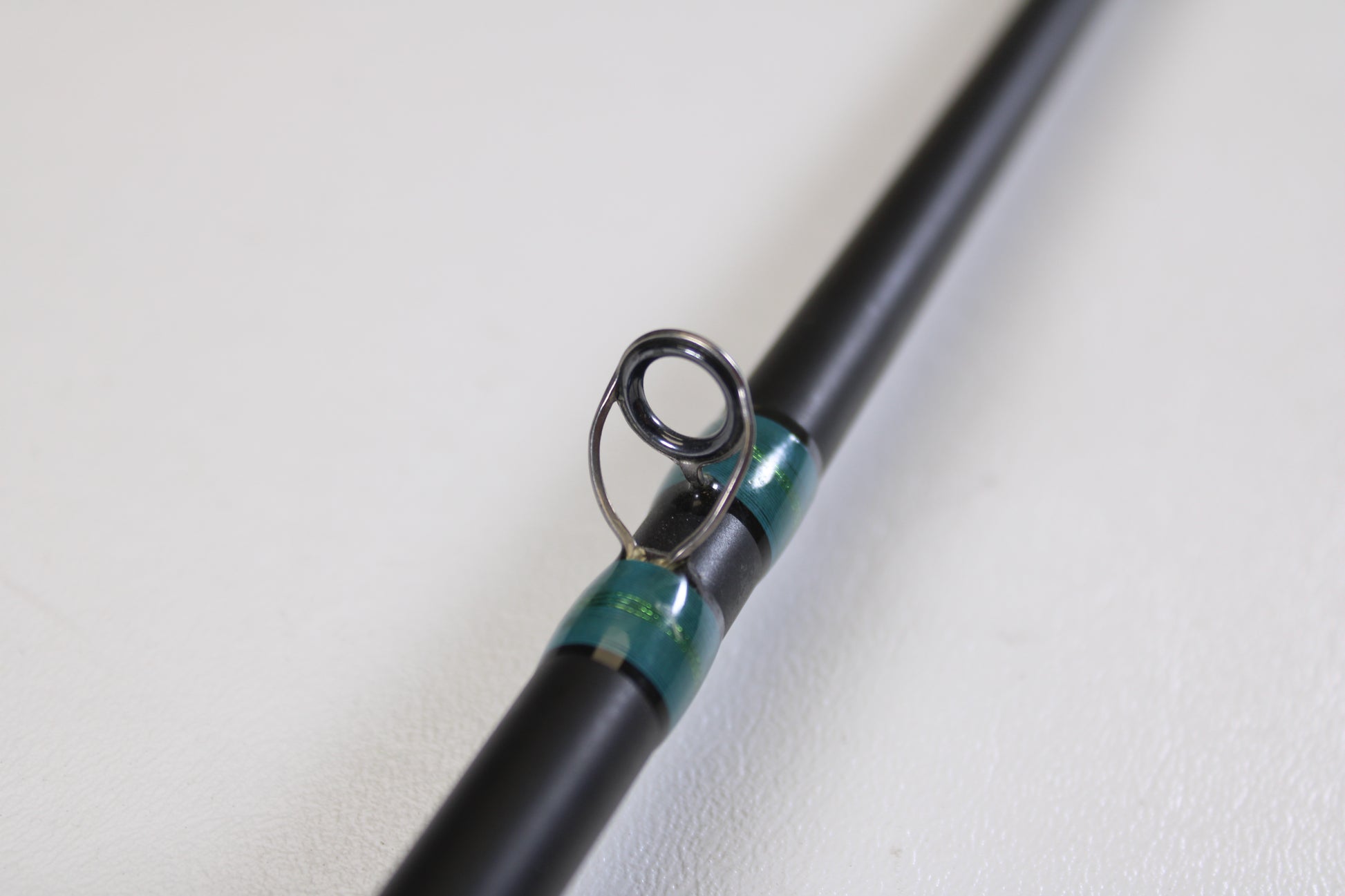 A close-up of the G. Loomis NRX 873c CRR 7'3" Medium Heavy used casting rod in excellent condition, featuring black guides with metallic green thread wraps—ideal for trade-in or earning store credit with G. Loomis gear.
