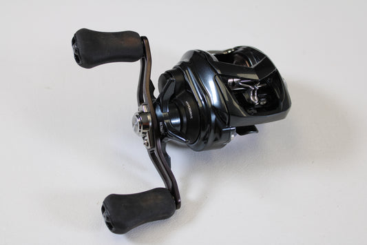A close-up of a used Daiwa Tatula SV 70 TTUSV70 6.3:1 RH casting reel in excellent condition with dual rubberized handles, on a white background. Trade in your gear through our Rod and Reel Trade-In Program for store credit!.