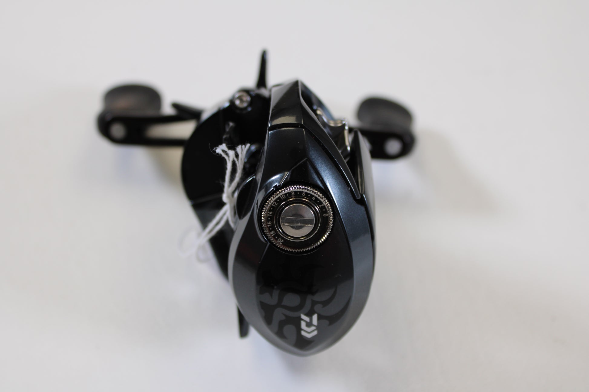 A close-up of a Daiwa Tatula SV 70 Used Casting Reel in excellent condition, featuring a black finish with silver details and handle on a white surface. Trade in your used gear for store credit with our Rod and Reel Trade-In Program.
