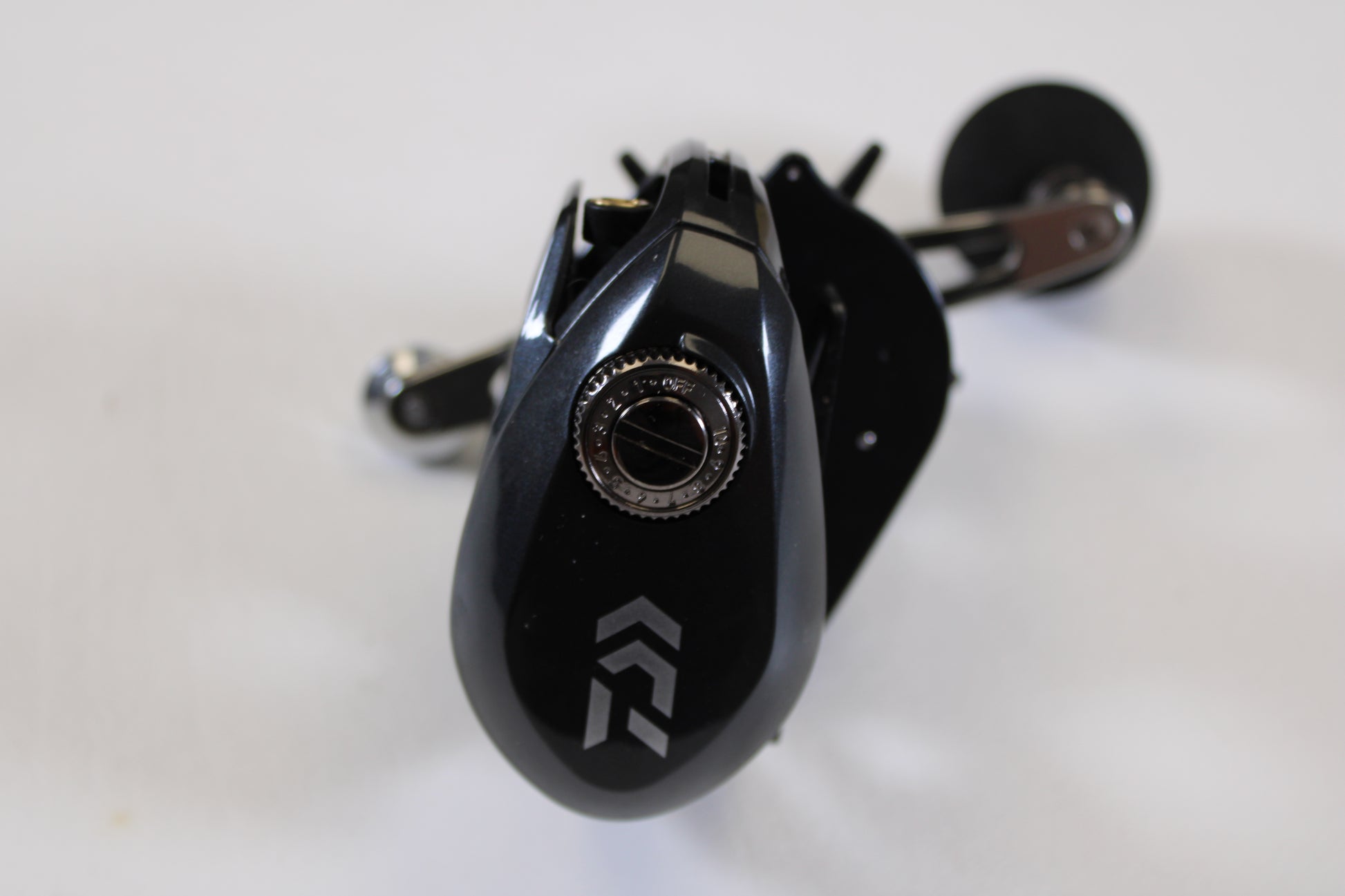 Close-up of a Daiwa Lexa 300 LX 300HL-P 7.4:1 LH Used Casting Reel in excellent condition with a silver adjustment knob and white geometric logo—perfect for upgrading through our Rod and Reel Trade-In Program for store credit. White background shown.