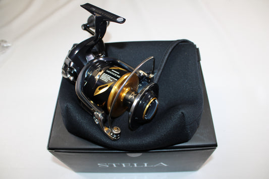 A Shimano Stella SW C STLSW20000PGC Used Spinning Reel in mint condition sits on a black cushion atop a Stella-branded box, ideal for anglers interested in rod and reel trade-in or upgrading used gear for store credit.
