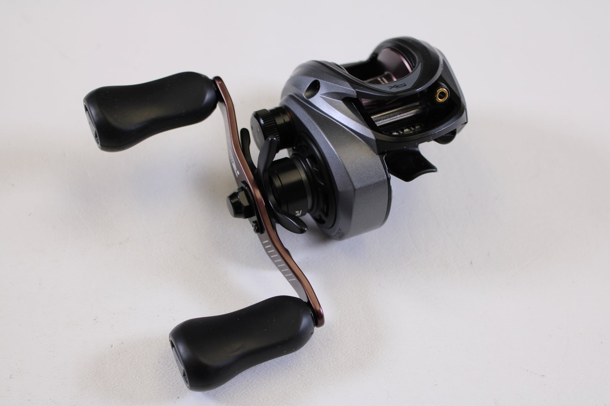 A close-up of an Abu Garcia Revo SX REVO5SXHSLP 7.3:1 RH used baitcasting reel in excellent condition, with black and silver finish and two black handles, photographed on a plain white background—great for reel trade-in or buying quality gear.