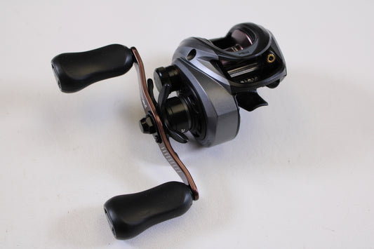 A close-up of an Abu Garcia Revo SX REVO5SXHSLP 7.3:1 RH used baitcasting reel in excellent condition, with black and silver finish and two black handles, photographed on a plain white background—great for reel trade-in or buying quality gear.