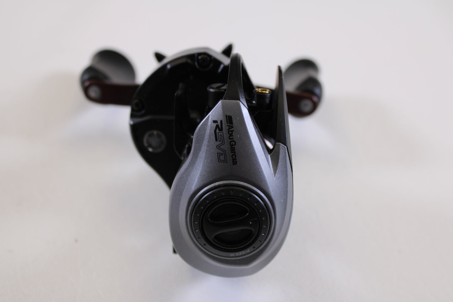 A close-up of an Abu Garcia Revo SX REVO5SXHSLP 7.3:1 RH used casting reel in excellent condition, featuring gray and black colors with visible adjustment dials, ideal for anyone seeking quality pre-owned fishing gear.