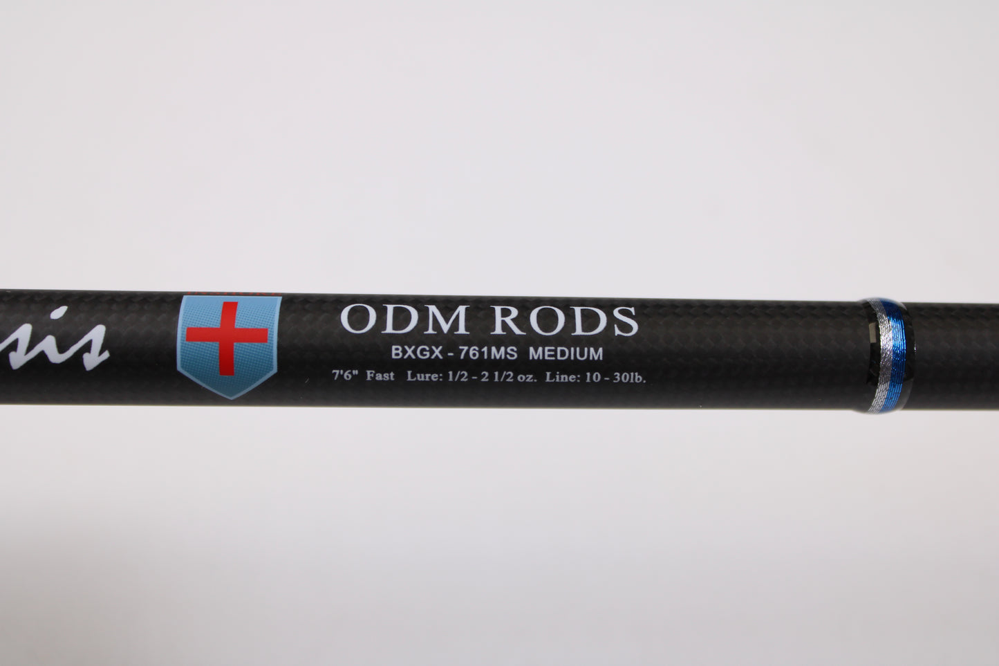 Close-up of an ODM Rods Genesis Inshore BXGX 761MS 7'6" Medium Used Spinning Rod in excellent condition, featuring a red and blue shield logo and specs in white—eligible for our rod and reel trade-in program for store credit.