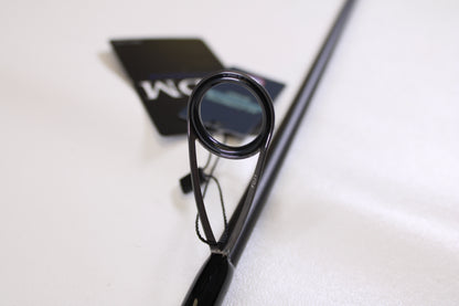 Close-up of an ODM Rods Genesis Inshore BXGX 761MS 7'6" Medium spinning rod guide ring, tags attached in the background—ideal for those looking to trade in or earn store credit on used fishing gear.