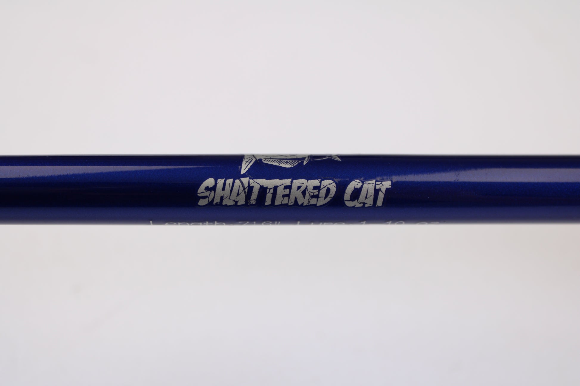 A close-up of the Shattered Cat 7'6" Heavy Used Casting Rod in excellent condition, featuring "SHATTERED CAT" in silver and a graphic above the text—ideal for those interested in used rods or our gear trade-in program.