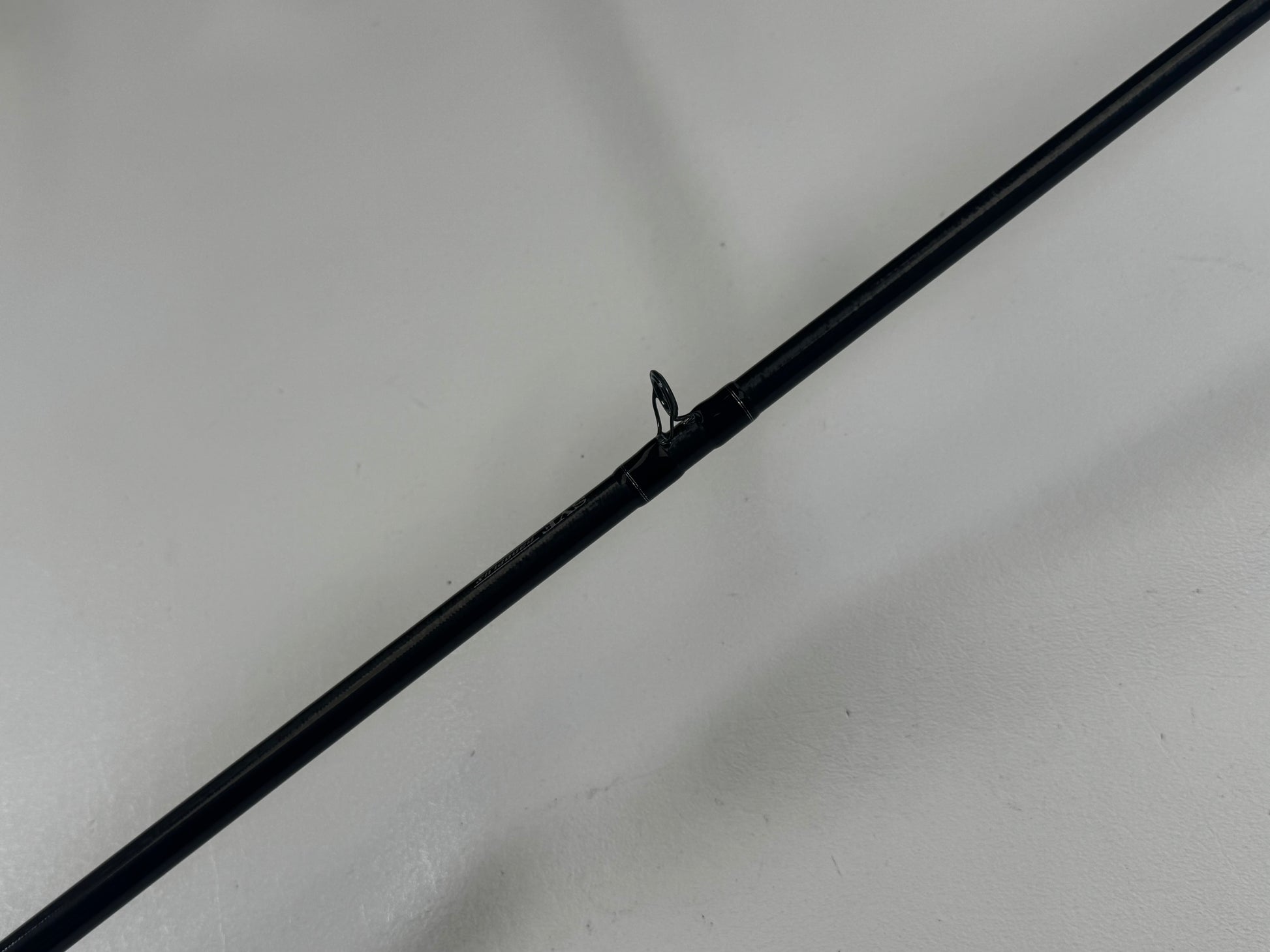 Close-up of a Daiwa Zillion 7'3" heavy used casting rod, black against a light gray backdrop. The focus is on a guide ring, showcasing its excellent condition—perfect for those interested in quality used gear and our Rod and Reel Trade-In Program.