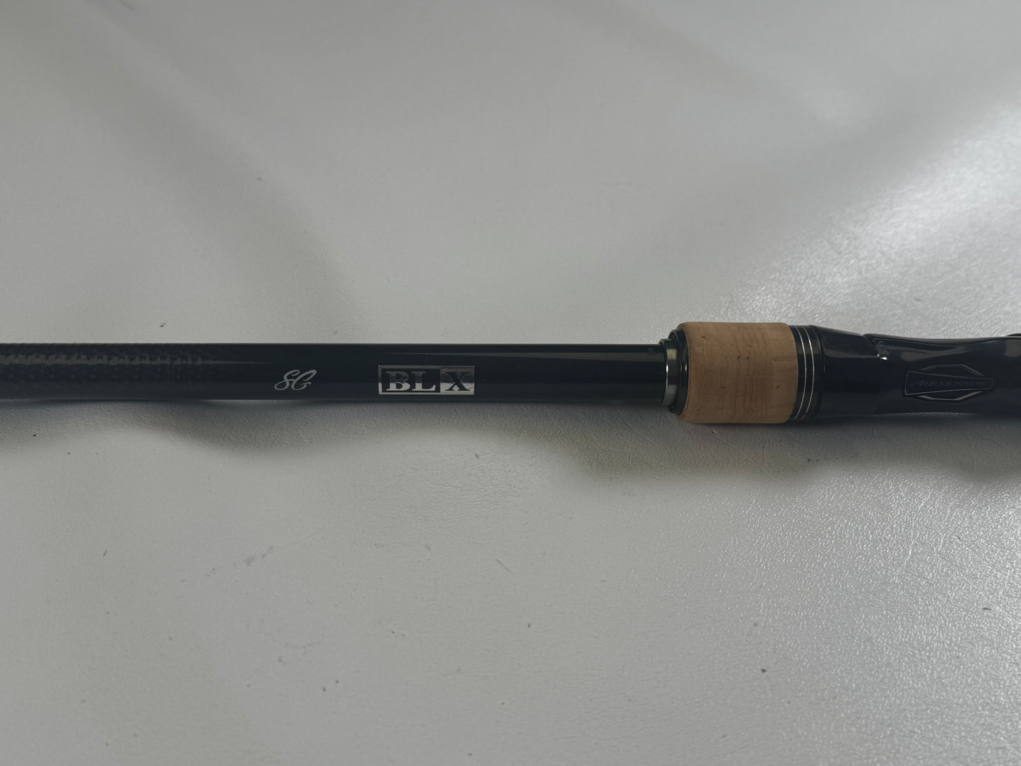 Close-up of a Daiwa BLX BLXSG7111XHXB used casting rod handle in excellent condition on a white surface. It displays silver "SG" and "BLX" markings, with a wood-colored grip section.