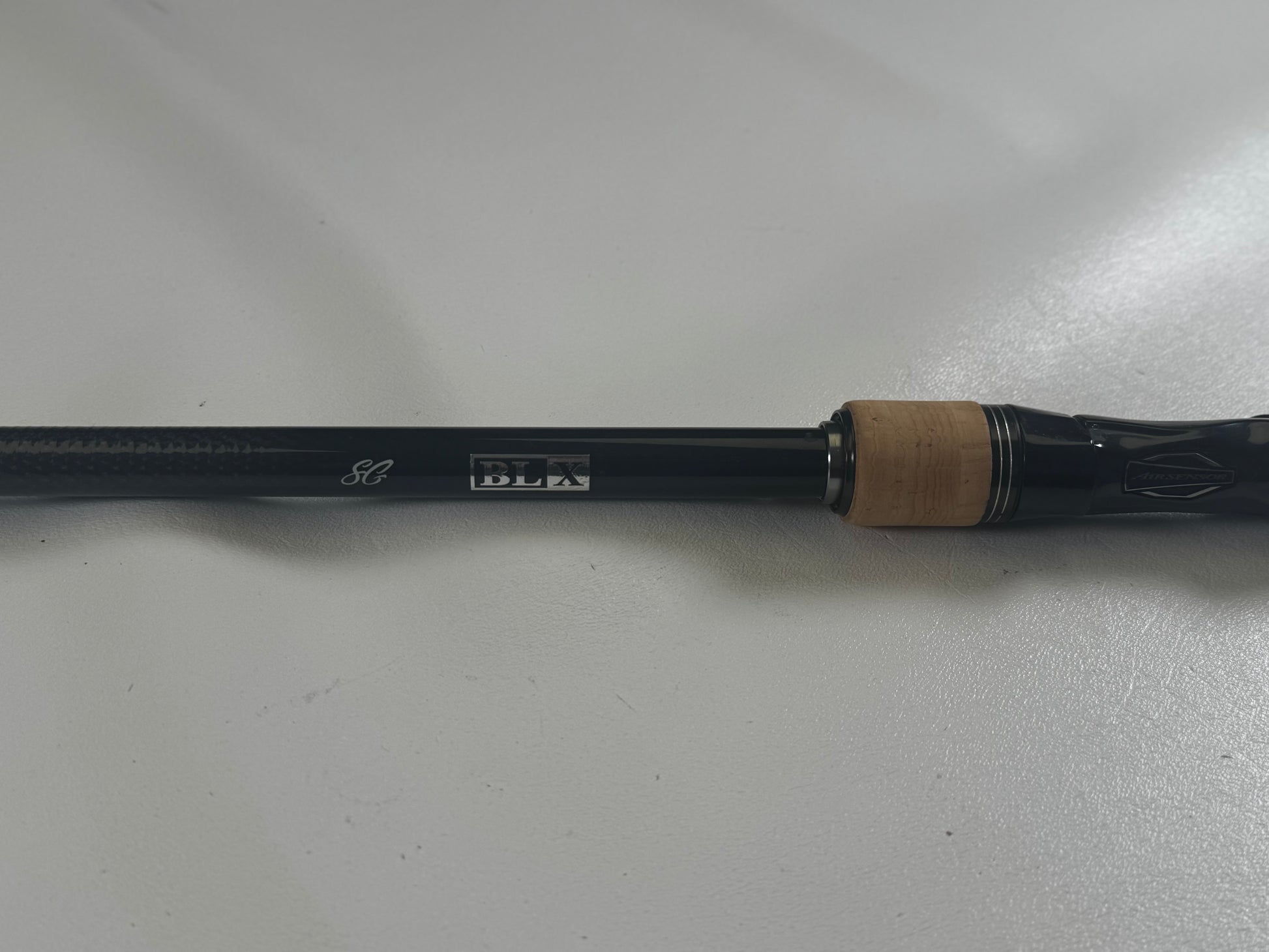 Close-up of a Daiwa BLX BLXSG7111XHXB used casting rod handle in excellent condition on a white surface. It displays silver "SG" and "BLX" markings, with a wood-colored grip section.