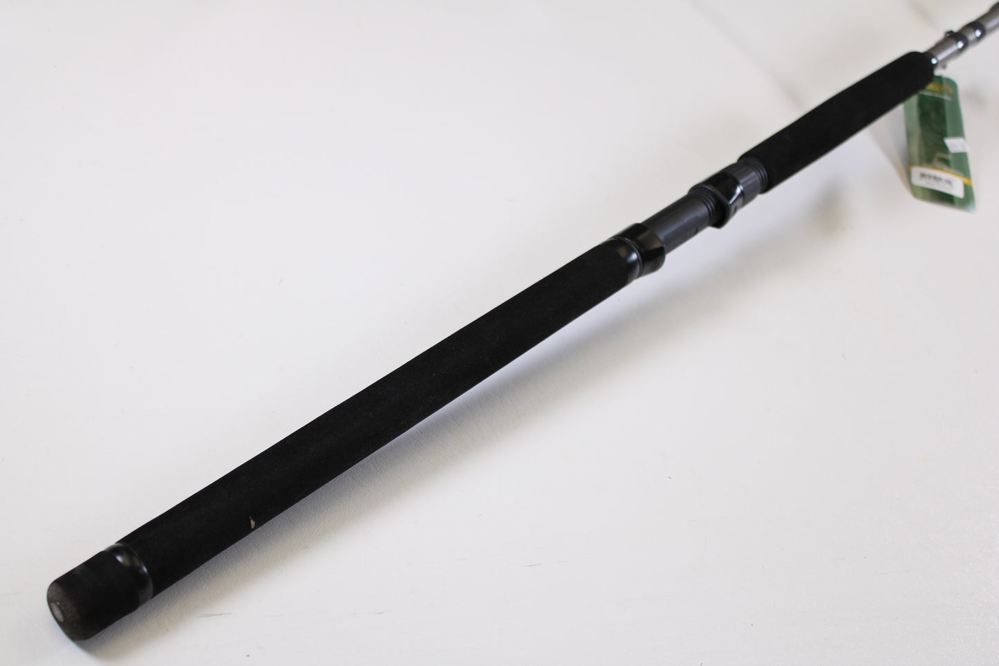 A close-up of the St. Croix Mojo Musky Trolling MMT90HM2 9'0" Heavy – a used casting rod in mint condition with a black foam grip, metal reel seat, and green tag, ideal for our Rod and Reel Trade-In Program. Plain white background.