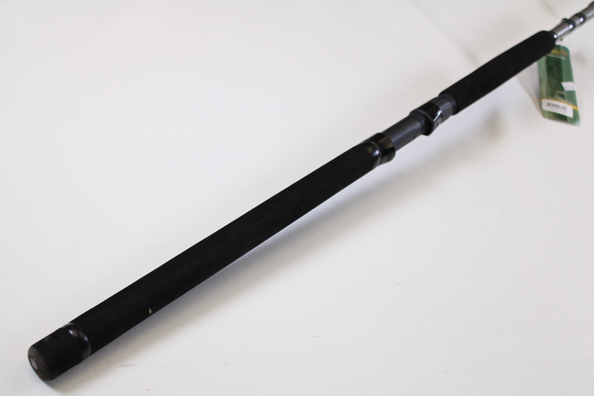 A close-up of the St. Croix Mojo Musky Trolling MMT90HM2 9'0" Heavy – a used casting rod in mint condition with a black foam grip, metal reel seat, and green tag, ideal for our Rod and Reel Trade-In Program. Plain white background.