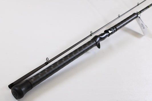 A close-up of the G. Loomis GCX Salmon 1083-2C SATR 9'0" Medium Heavy 2 Piece Used Casting Rod in mint condition, displayed diagonally to highlight its multiple guide rings and textured handle, from our rod and reel trade-in program.