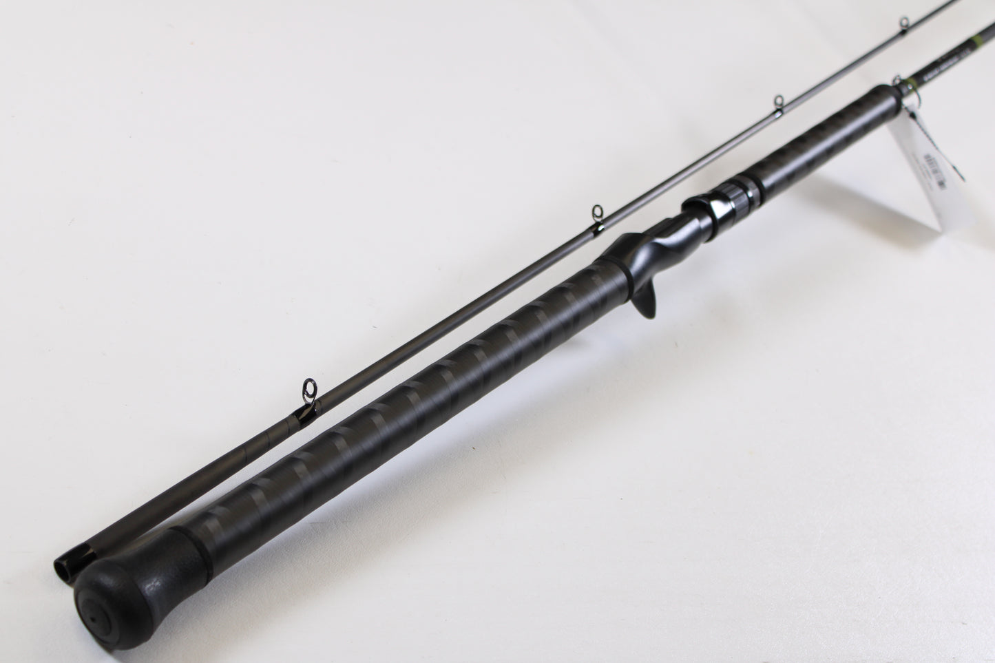 A close-up of the G. Loomis GCX Salmon 1083-2C SATR 9'0" Medium Heavy 2 Piece Used Casting Rod in mint condition, displayed diagonally to highlight its multiple guide rings and textured handle, from our rod and reel trade-in program.