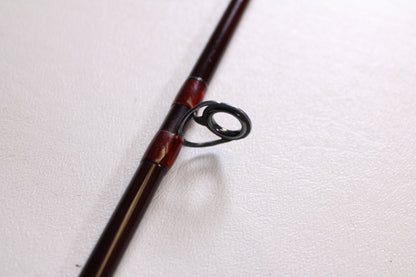 A close-up of a G. Loomis IM6 CR 664C 5'6" Heavy used casting rod, showing its metal guide ring on a white surface—ideal for those interested in the G. Loomis brand or considering a rod and reel trade-in.