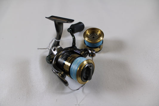 A Shimano Sustain SA1000FE Used Spinning Reel in fair condition, spooled with blue line, is displayed on a white surface with an extra spool—ideal for your Rod and Reel Trade-In or adding to your Used Gear collection.